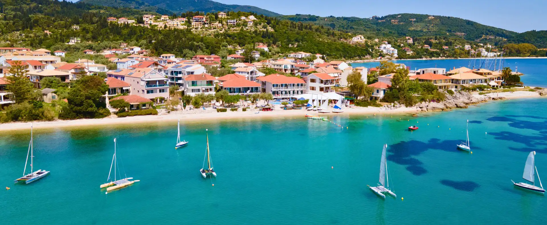Aerial view of Nikiana Beach Club on Lefkas, with dinghies moored in the turquoise bay