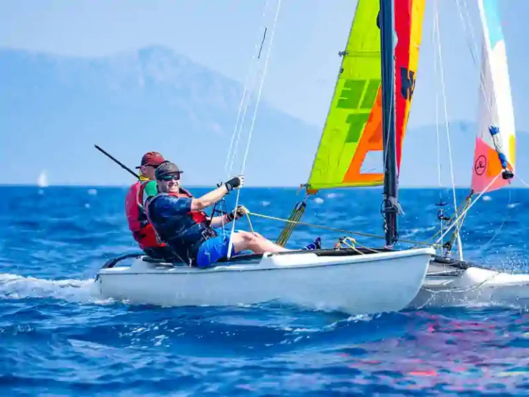 Sailors on a small boat with bright sails in the bay at Nikiana Beach Club